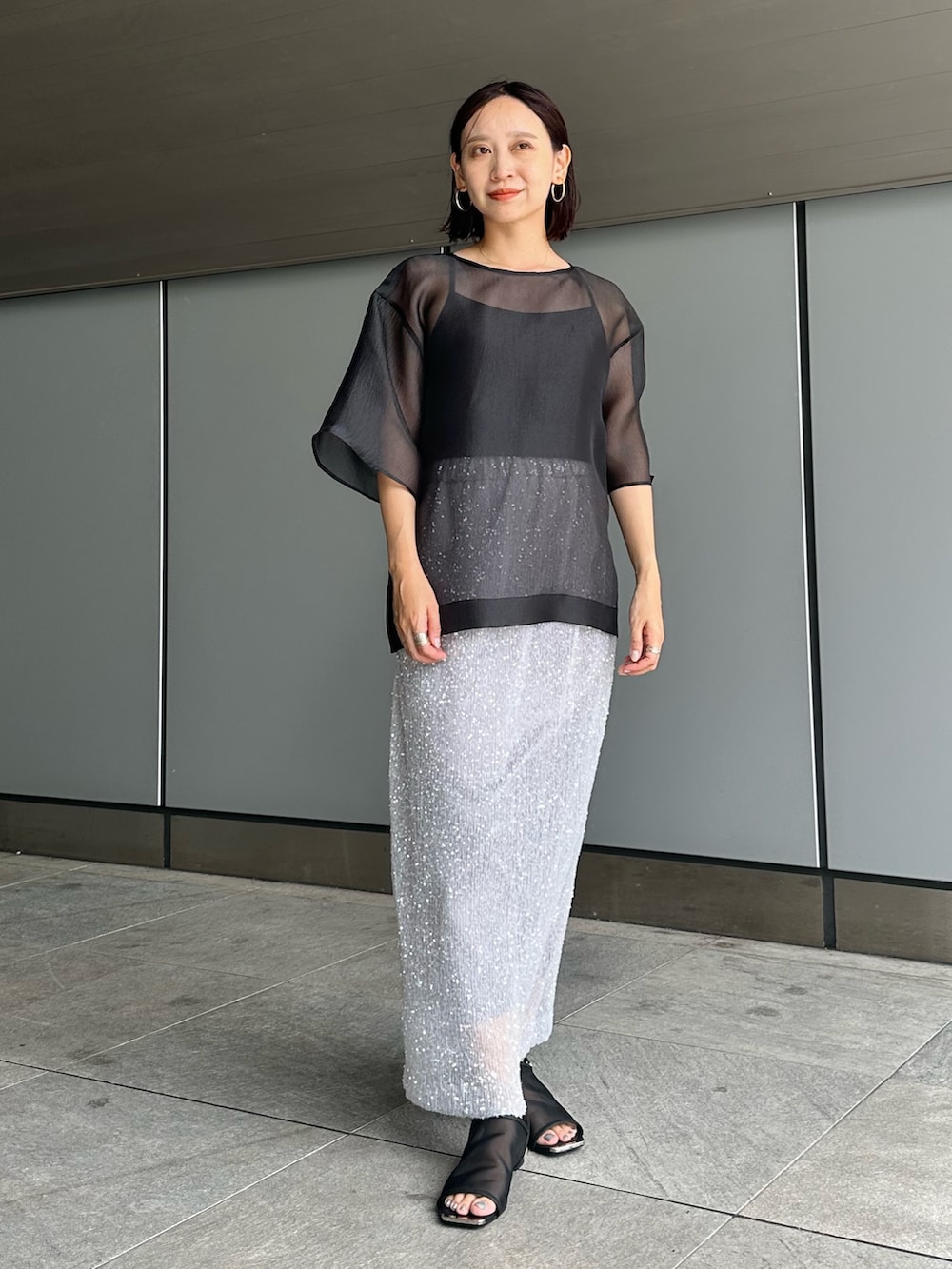 ブラック系のシャツ/ブラウス、シルバー系のスカートを着用したレディースの夏コーディネートの2枚目の写真