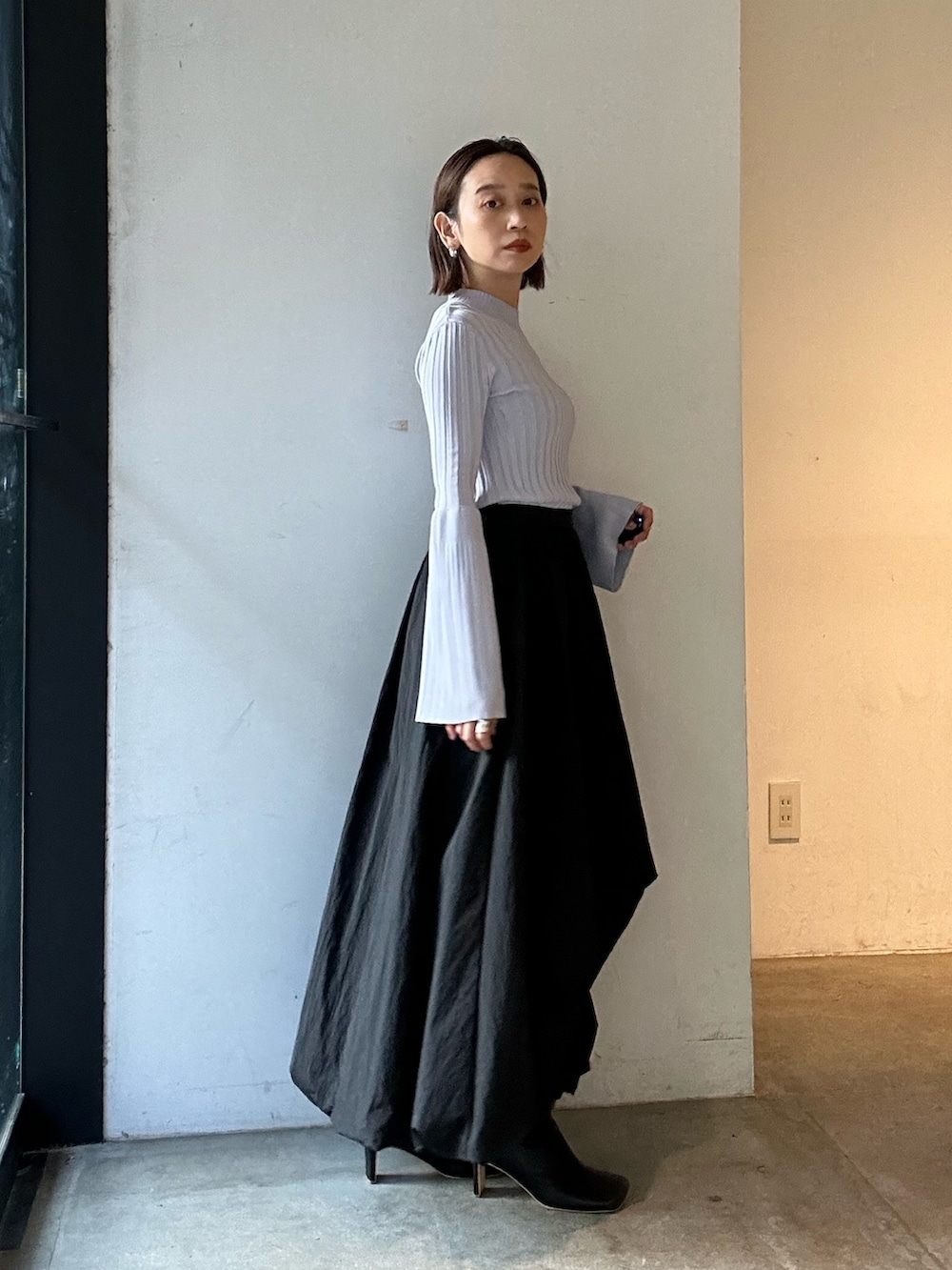 ブラック系のスカート、ブラック系のブーツ、パープル系のニット/セーターを着用したレディースの冬コーディネートの3枚目の写真