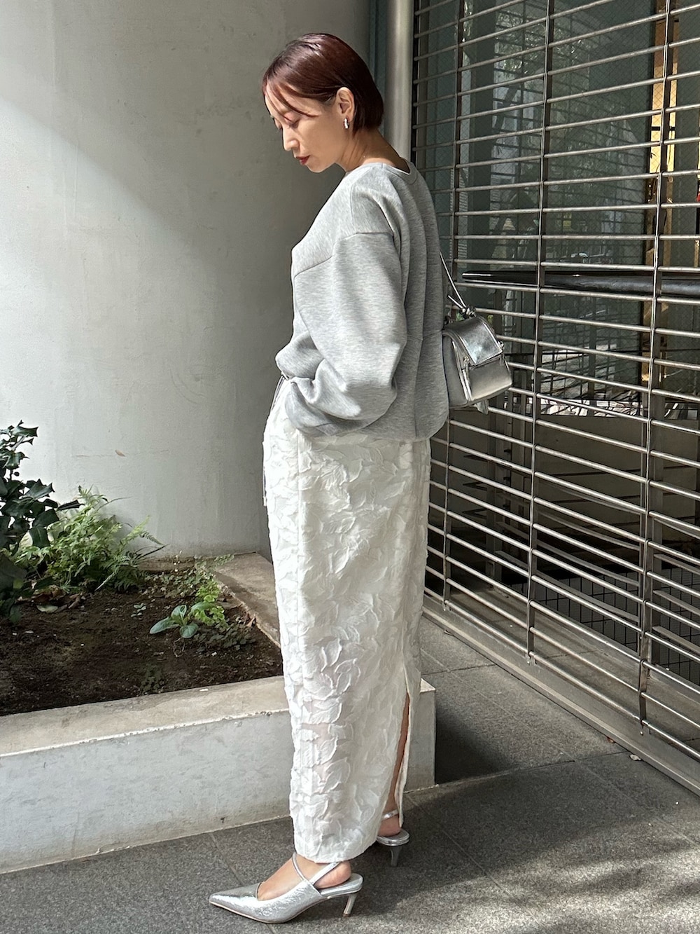 グレー系のスウェット、ホワイト系のスカート、シルバー系のボストンバッグを着用したレディースの冬コーディネートの4枚目の写真