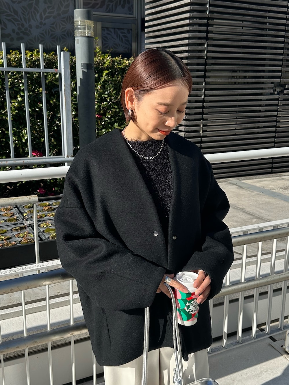 ブラック系のノーカラージャケット、シルバー系のボストンバッグ、ホワイト系のその他パンツを着用したレディースの冬コーディネートの6枚目の写真