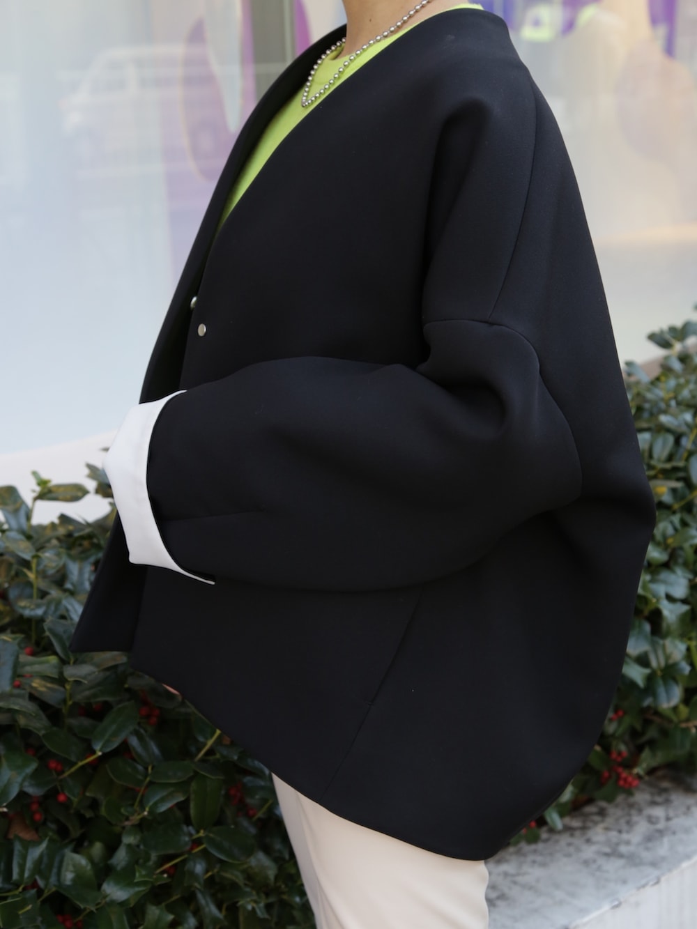 ブラック系のノーカラーコート、ベージュ系のその他パンツ、ブルー系のスニーカーを着用したレディースの冬コーディネートの3枚目の写真