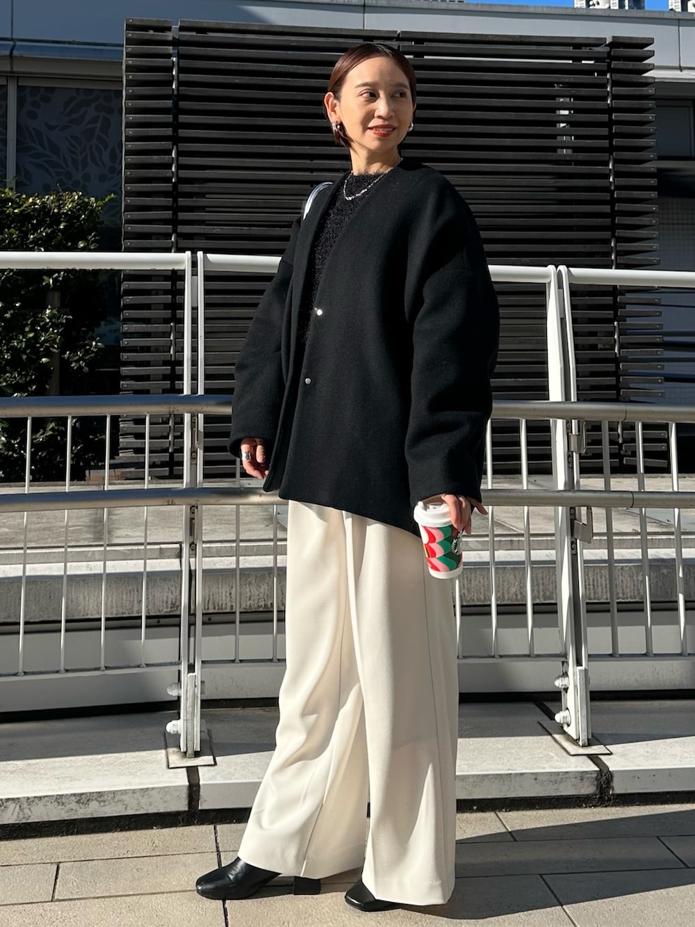 ブラック系のノーカラージャケット、シルバー系のボストンバッグ、ホワイト系のその他パンツを着用したレディースの冬コーディネートの4枚目の写真