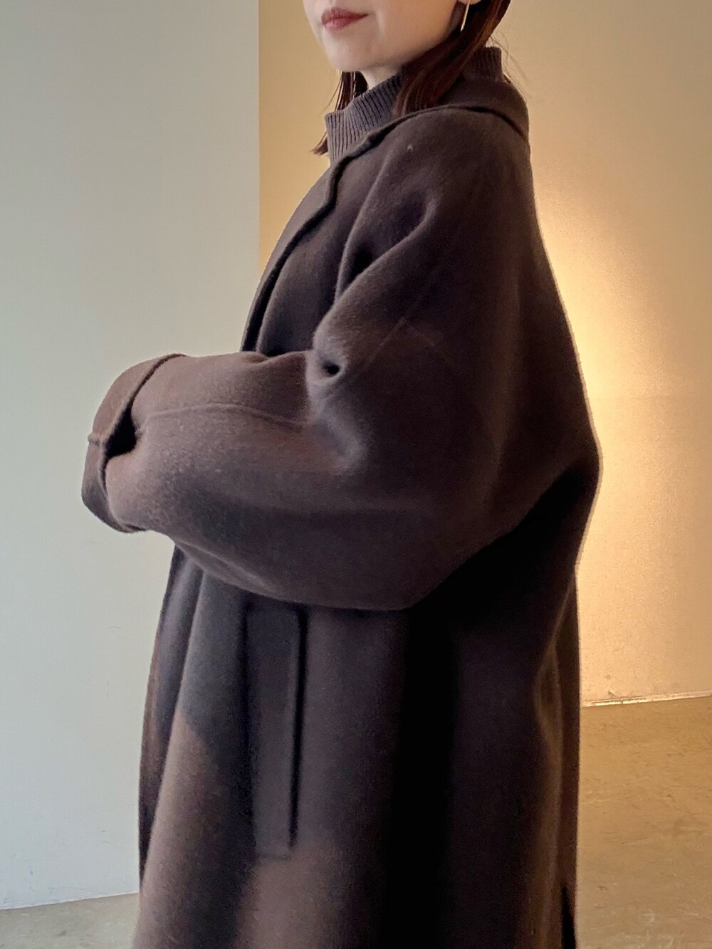 ブラウン系のチェスターコート、ブラック系のスカート、ブラウン系のニット/セーターを着用したレディースの秋コーディネートの6枚目の写真