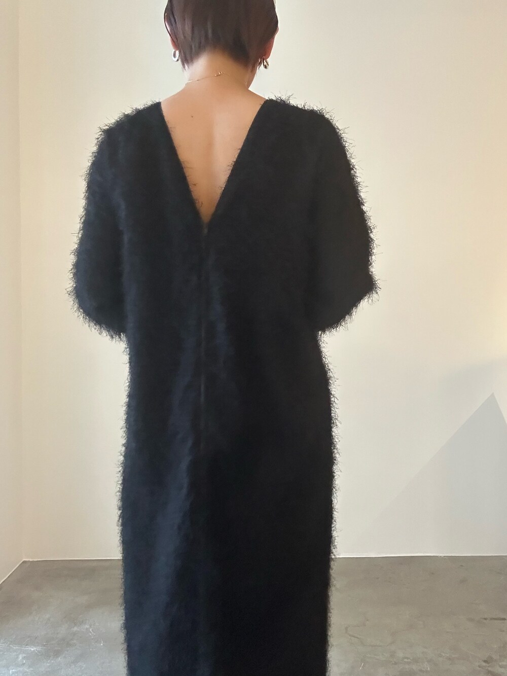 ブラック系のワンピース、シルバー系のハンドバッグ、ブラック系のブーツを着用したレディースの秋コーディネートの5枚目の写真