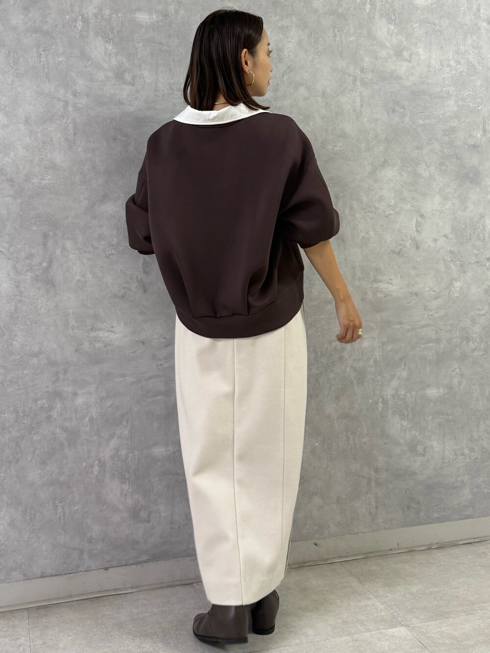 ブラウン系のTシャツ/カットソー、ホワイト系のスカート、ブラウン系のブーツを着用したレディースの秋コーディネートの3枚目の写真