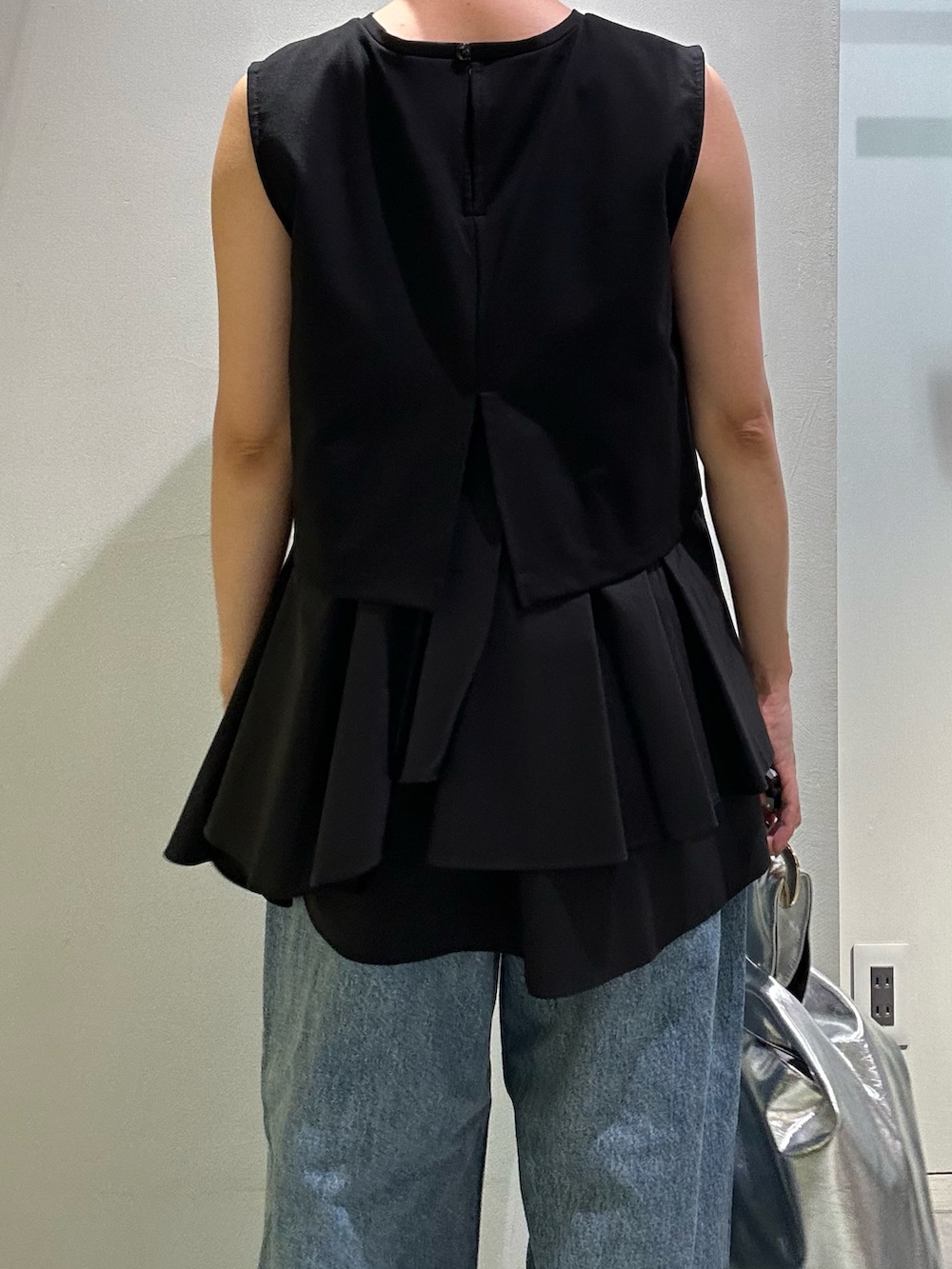 ブルー系のデニムパンツ、シルバー系のハンドバッグ、ブラック系のタンクトップを着用したレディースの夏コーディネートの6枚目の写真