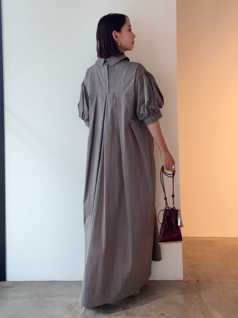 グレー系のワンピース、シルバー系のパンプス、レッド系のショルダーバッグを着用したレディースの夏コーディネートの3枚目の写真