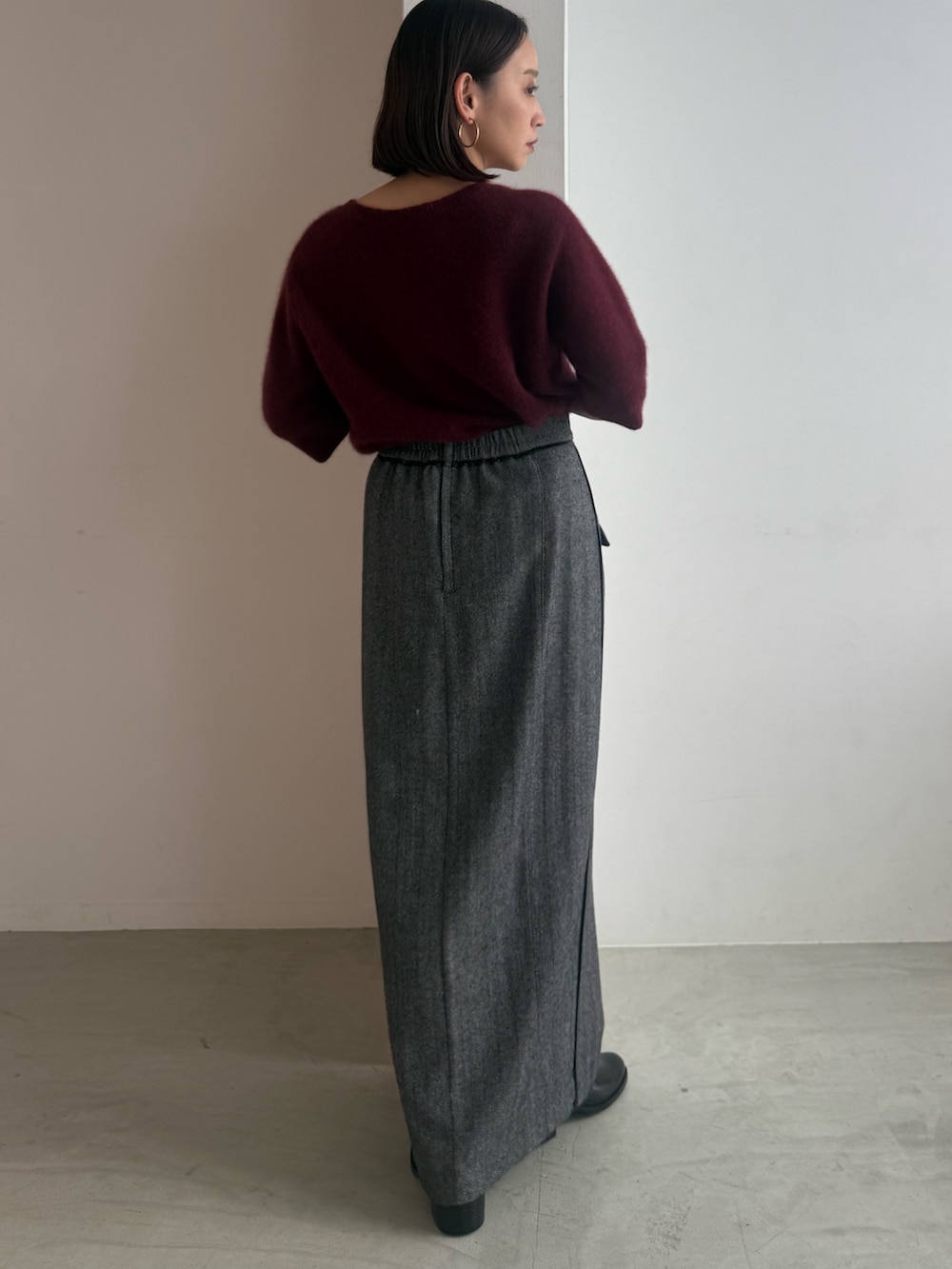 レッド系のニット/セーター、グレー系のスカート、ブラック系のパンプスを着用したレディースの秋コーディネートの3枚目の写真