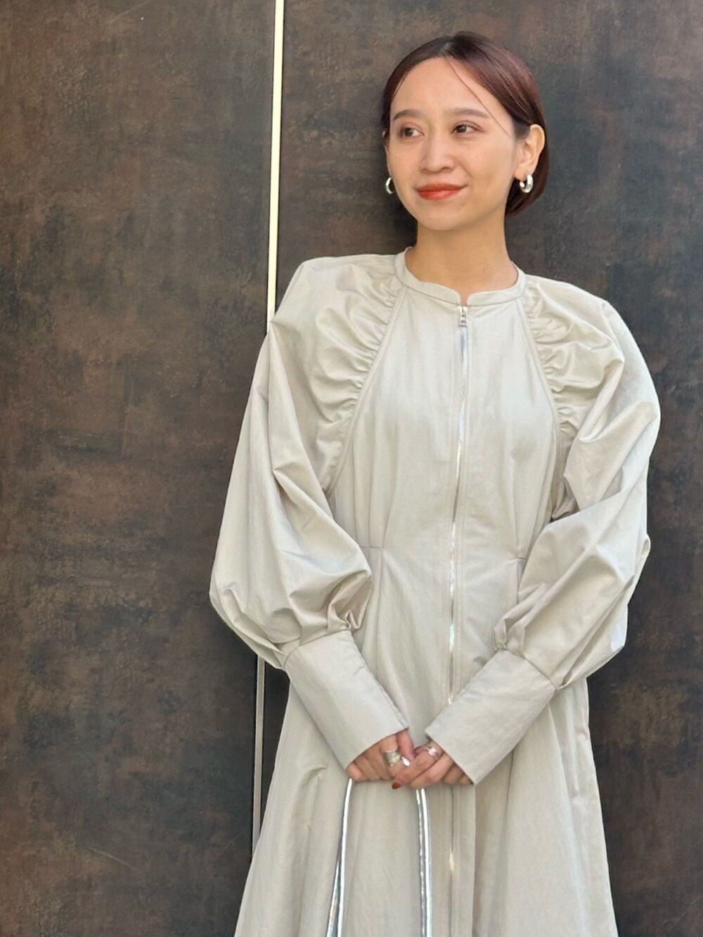 シルバー系のボストンバッグ、ブラック系のブーツ、ベージュ系のワンピースを着用したレディースの冬コーディネートの8枚目の写真