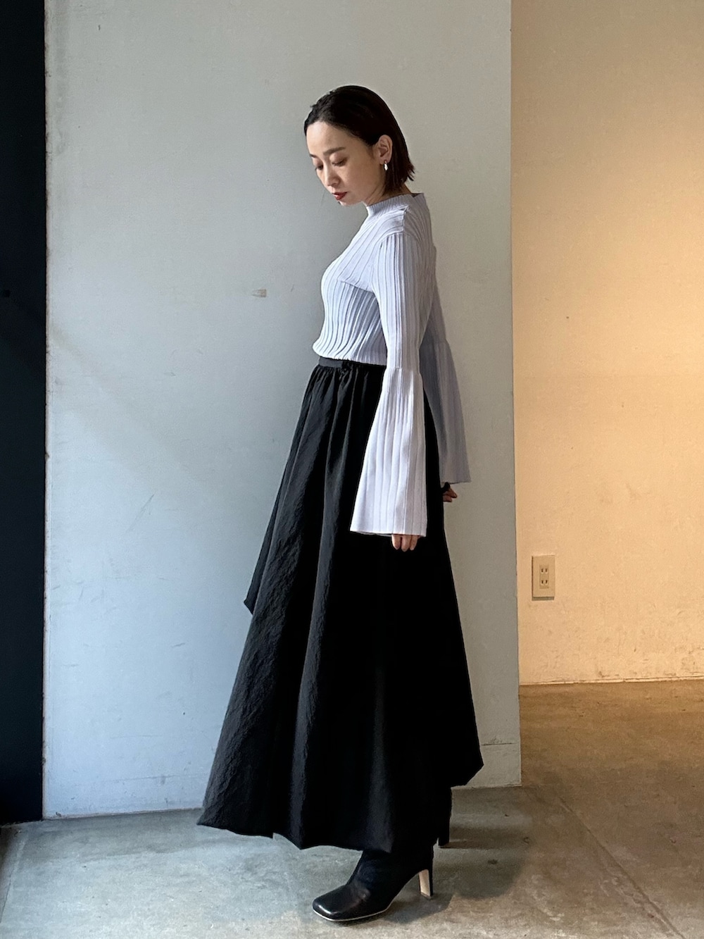 ブラック系のスカート、ブラック系のブーツ、パープル系のニット/セーターを着用したレディースの冬コーディネートの5枚目の写真