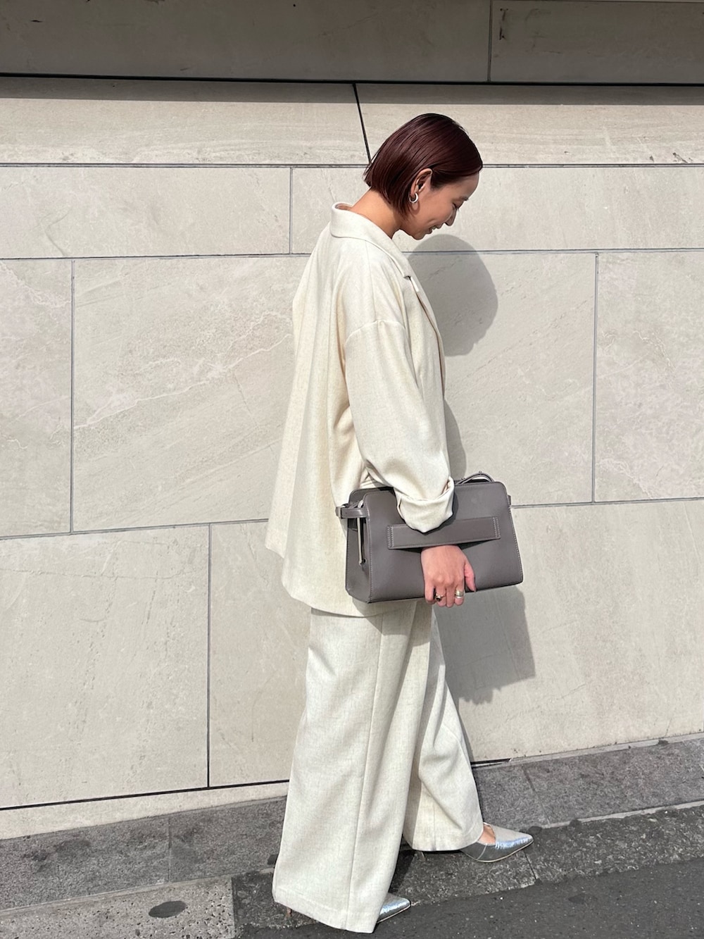 グレー系のハンドバッグ、ベージュ系のその他パンツ、シルバー系のサンダルを着用したレディースの春コーディネートの4枚目の写真