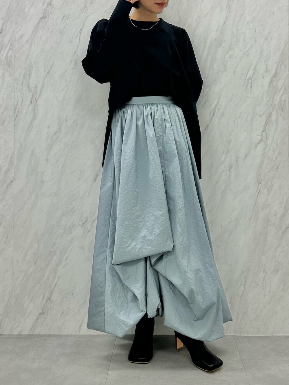 ブルー系のスカート、ブラック系のTシャツ/カットソー、ブラック系のブーツを着用したレディースの秋コーディネートの2枚目の写真