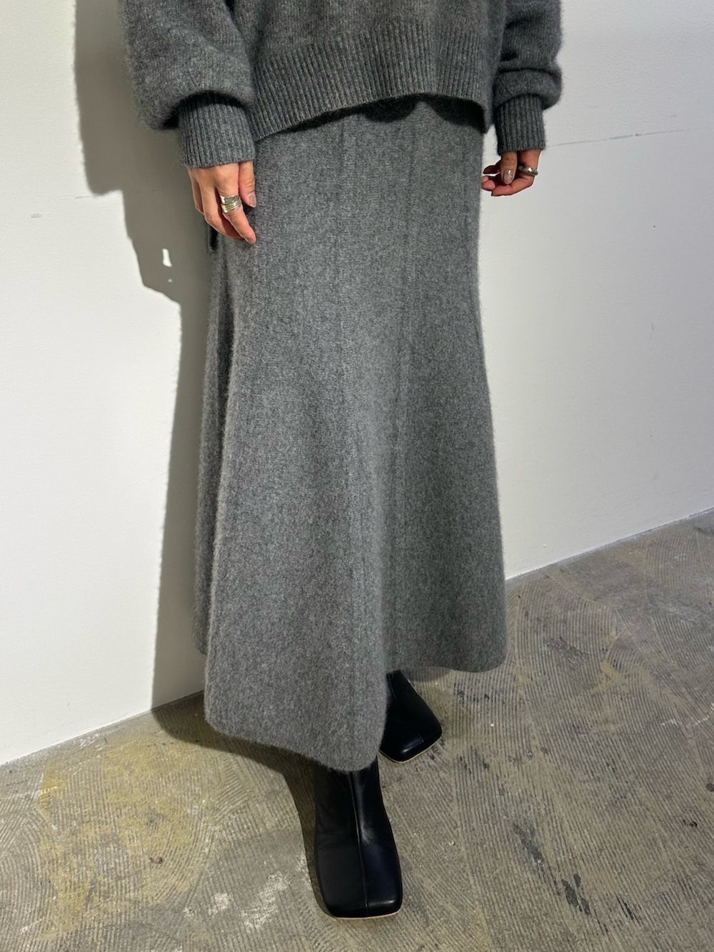 パープル系のノーカラージャケット、グレー系のスカート、ブラック系のブーツを着用したレディースの秋コーディネートの9枚目の写真