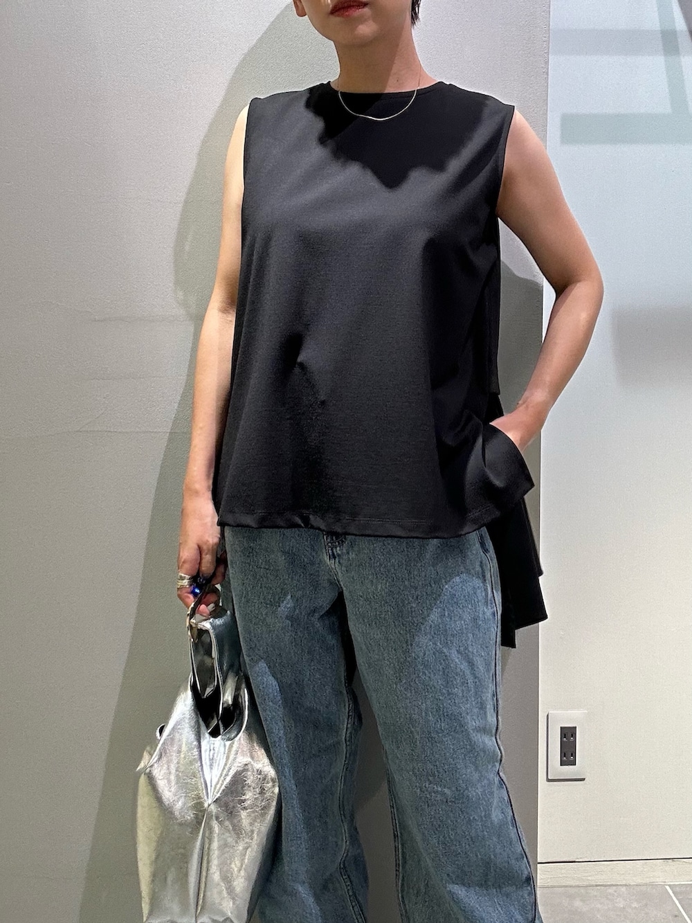 ブルー系のデニムパンツ、シルバー系のハンドバッグ、ブラック系のタンクトップを着用したレディースの夏コーディネートの5枚目の写真