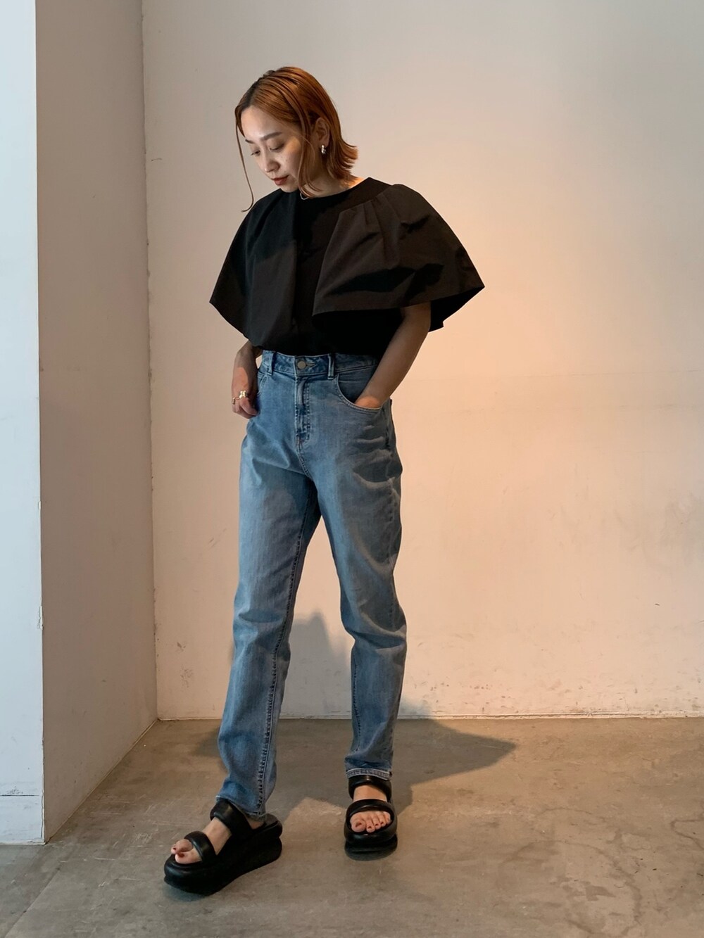 ブラック系のTシャツ/カットソー、ブルー系のデニムパンツ、ブラック系のサンダルを着用したレディースの春コーディネートの5枚目の写真