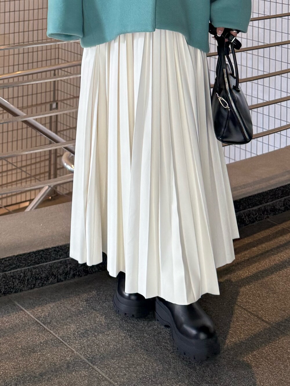 ホワイト系のニット/セーター、ホワイト系のスカート、グリーン系のノーカラージャケットを着用したレディースの秋コーディネートの7枚目の写真