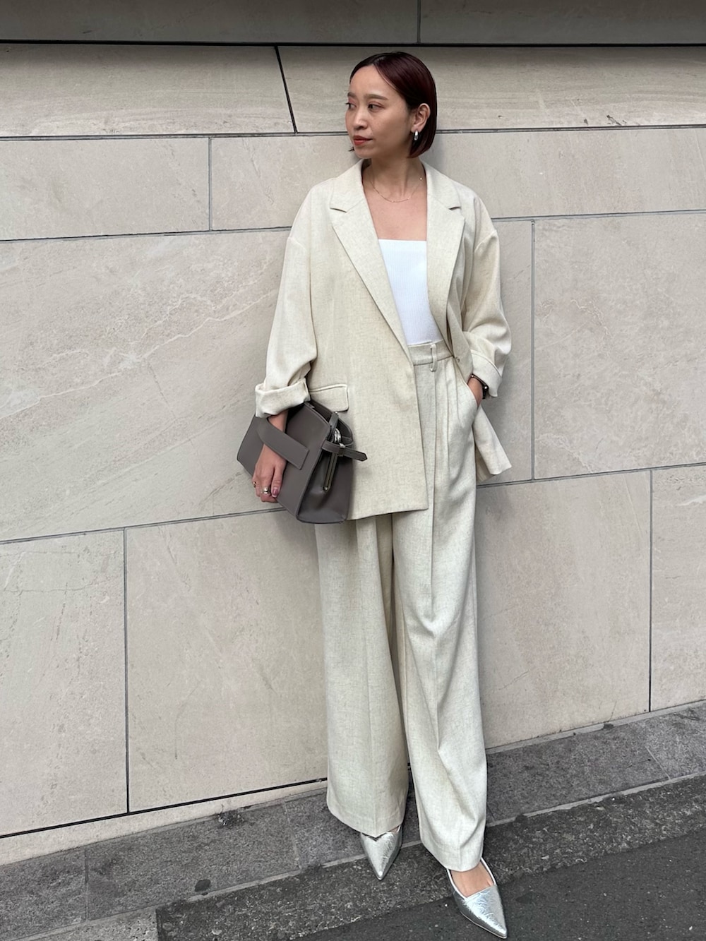 グレー系のハンドバッグ、ベージュ系のその他パンツ、シルバー系のサンダルを着用したレディースの春コーディネートの2枚目の写真