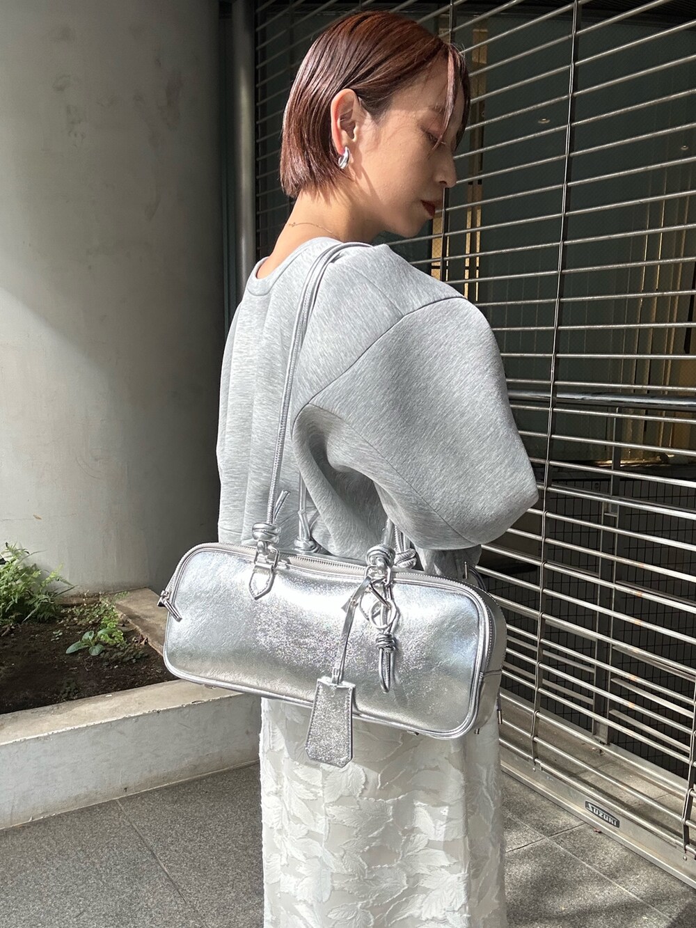 グレー系のスウェット、ホワイト系のスカート、シルバー系のボストンバッグを着用したレディースの冬コーディネートの8枚目の写真