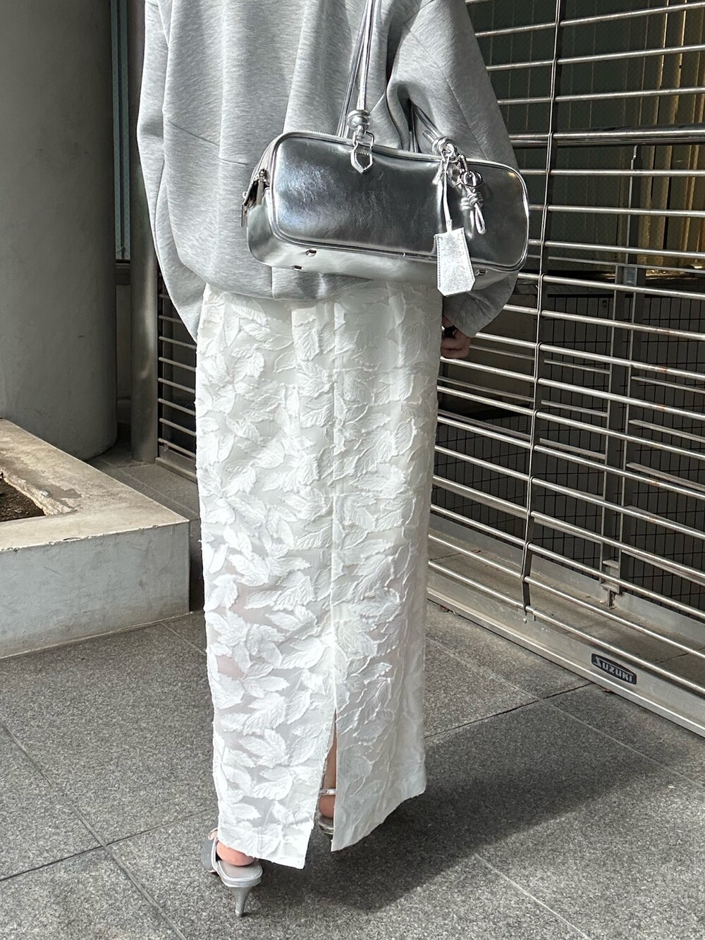 グレー系のスウェット、ホワイト系のスカート、シルバー系のボストンバッグを着用したレディースの冬コーディネートの10枚目の写真