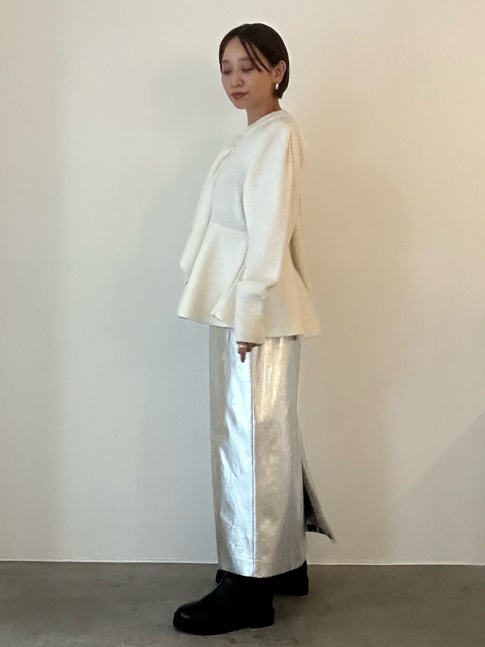 ホワイト系のニット/セーター、ブラック系のブーツ、シルバー系のスカートを着用したレディースの秋コーディネートの4枚目の写真