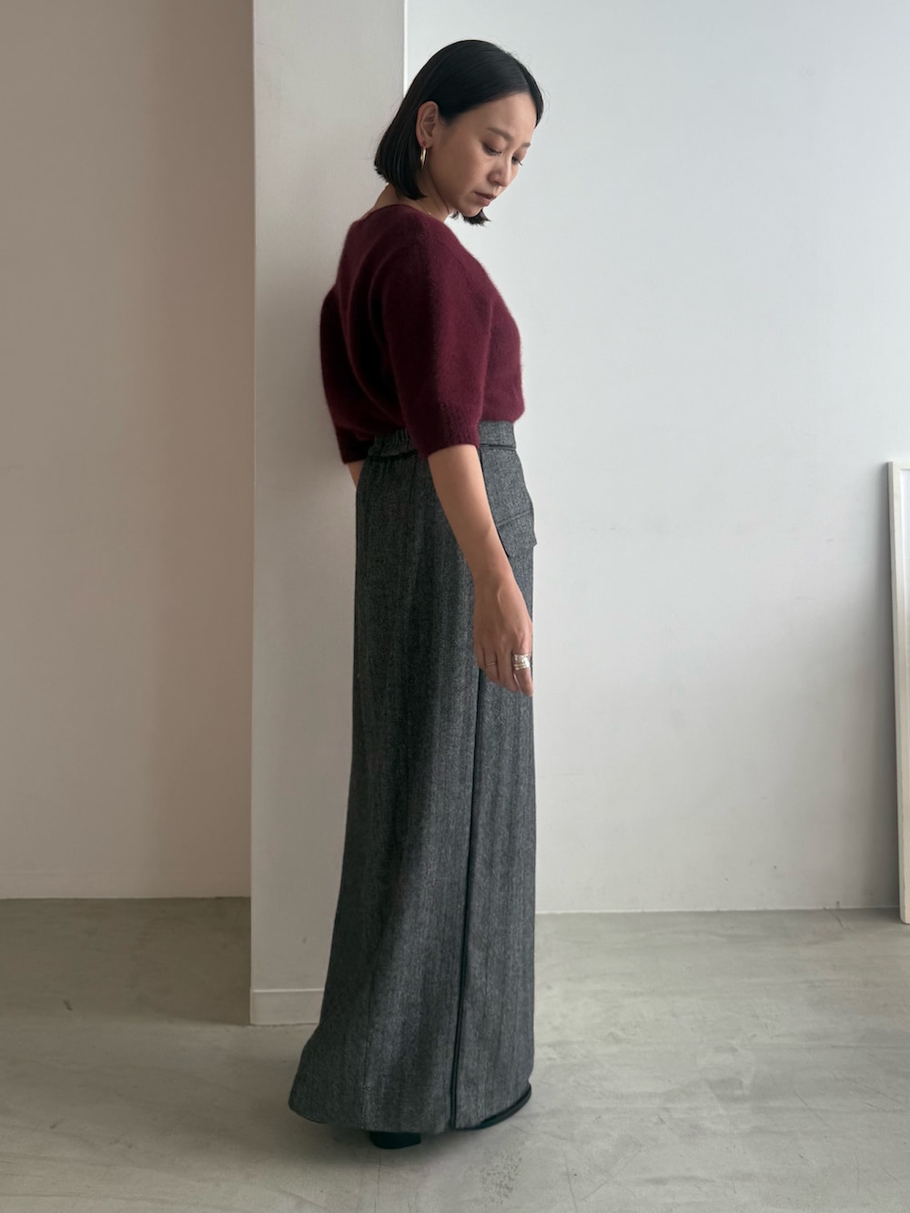 レッド系のニット/セーター、グレー系のスカート、ブラック系のパンプスを着用したレディースの秋コーディネートの2枚目の写真