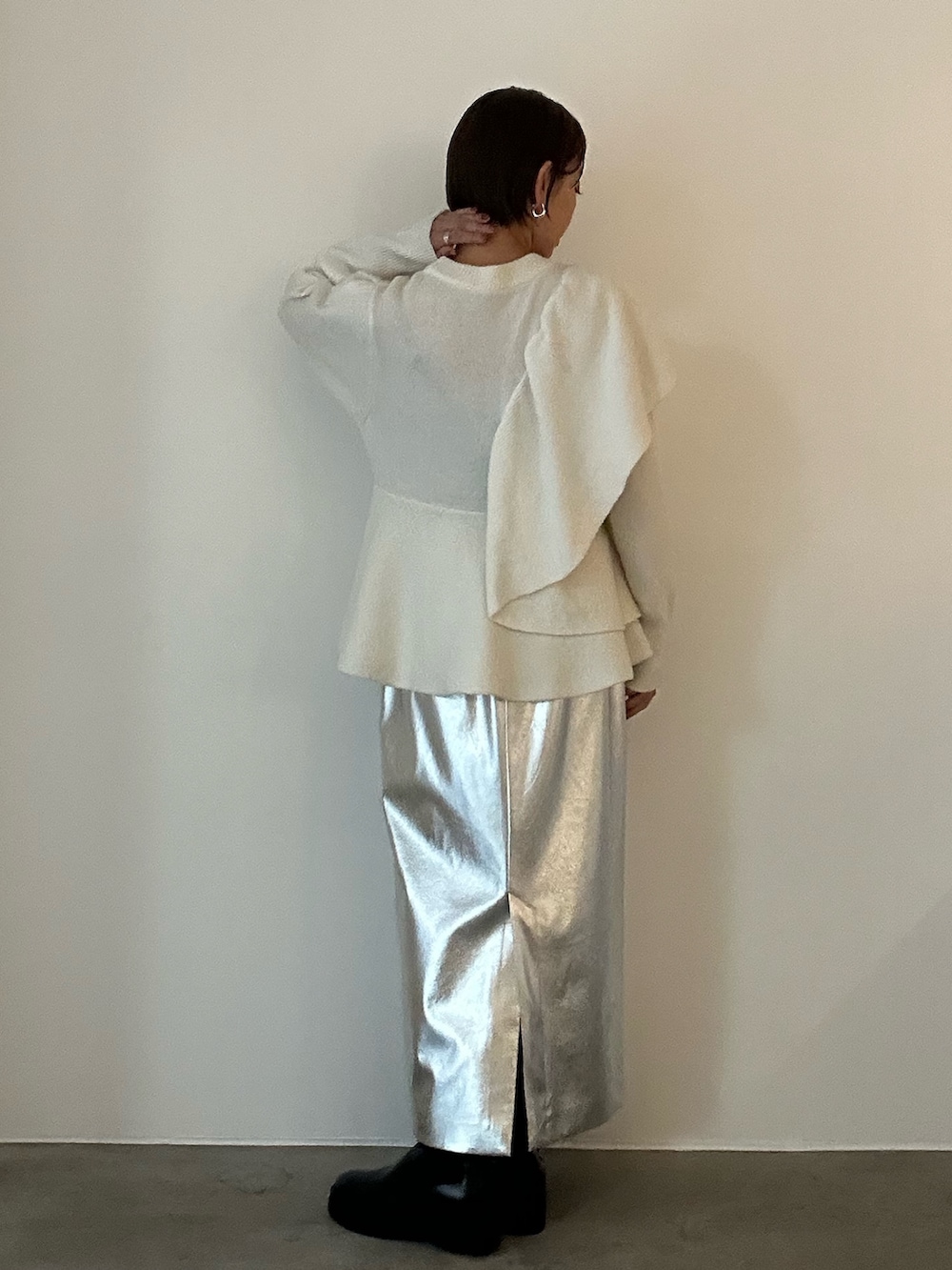 ホワイト系のニット/セーター、ブラック系のブーツ、シルバー系のスカートを着用したレディースの秋コーディネートの7枚目の写真