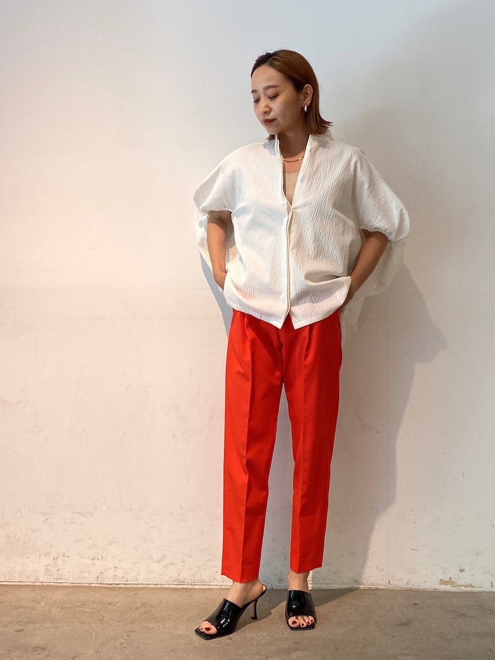 レッド系のその他パンツ、ホワイト系のシャツ/ブラウス、ブラック系のサンダルを着用したレディースの春コーディネートの3枚目の写真