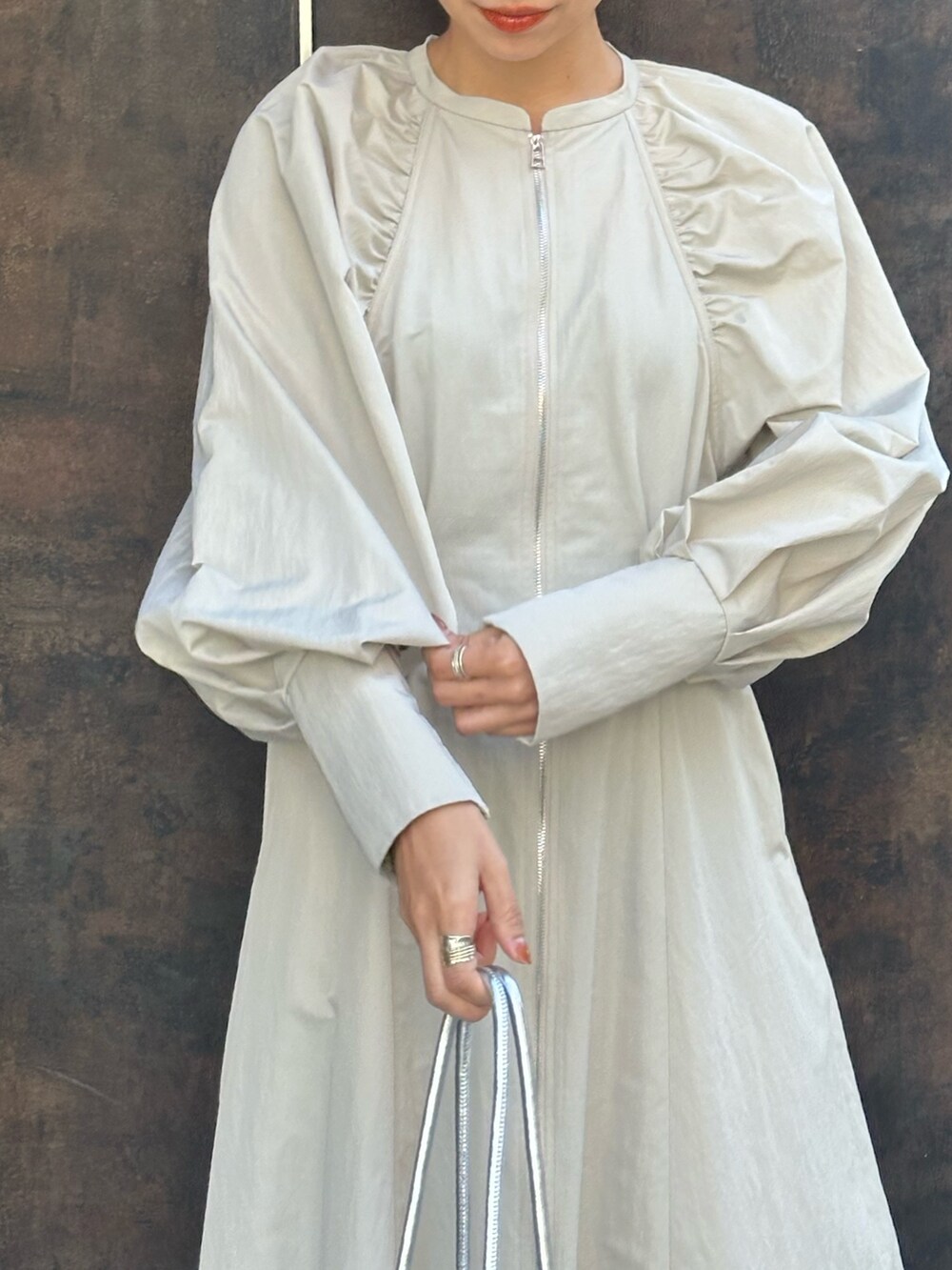 シルバー系のボストンバッグ、ブラック系のブーツ、ベージュ系のワンピースを着用したレディースの冬コーディネートの5枚目の写真