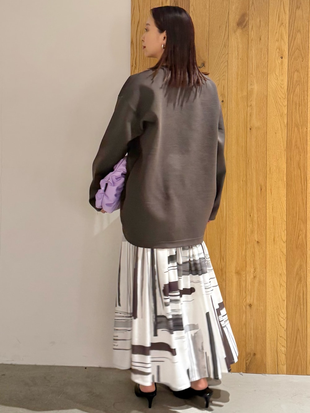 ホワイト系のワンピース、ブラック系のパンプス、パープル系のハンドバッグを着用したレディースの冬コーディネートの3枚目の写真