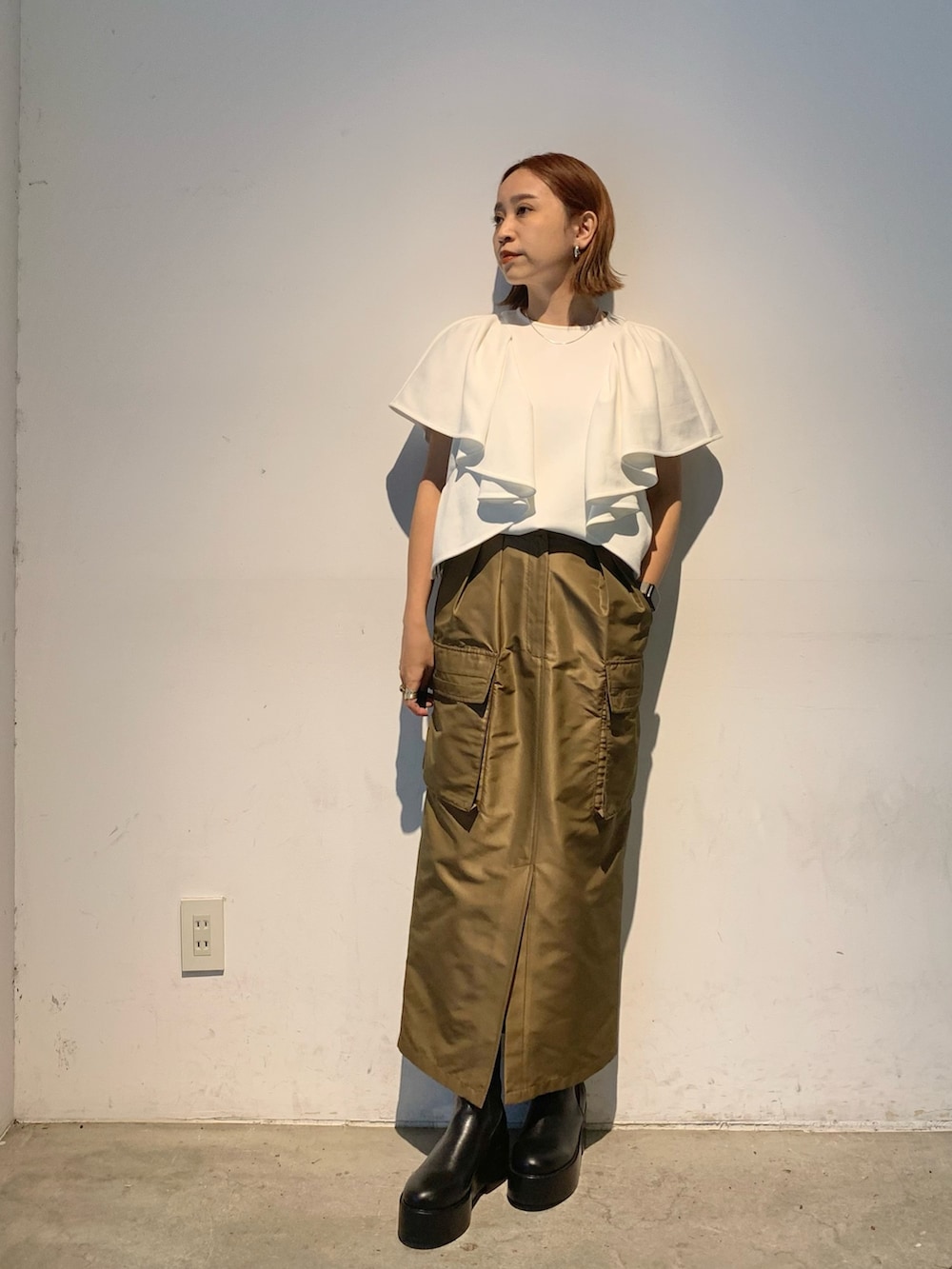 ホワイト系のTシャツ/カットソー、ブラウン系のスカート、ブラック系のブーツを着用したレディースの春コーディネートの3枚目の写真