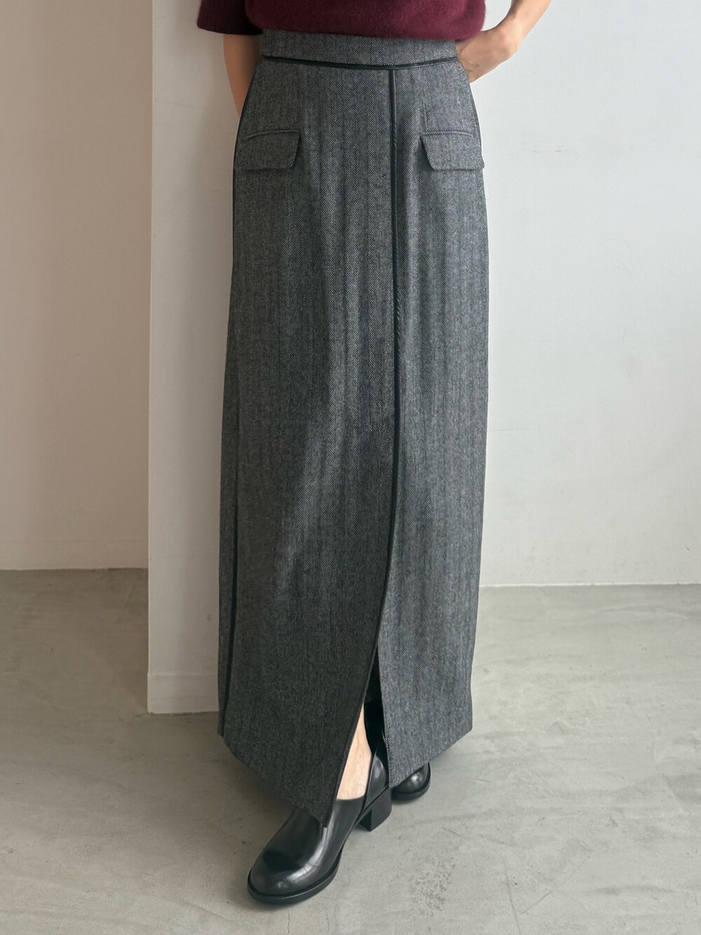 レッド系のニット/セーター、グレー系のスカート、ブラック系のパンプスを着用したレディースの秋コーディネートの6枚目の写真