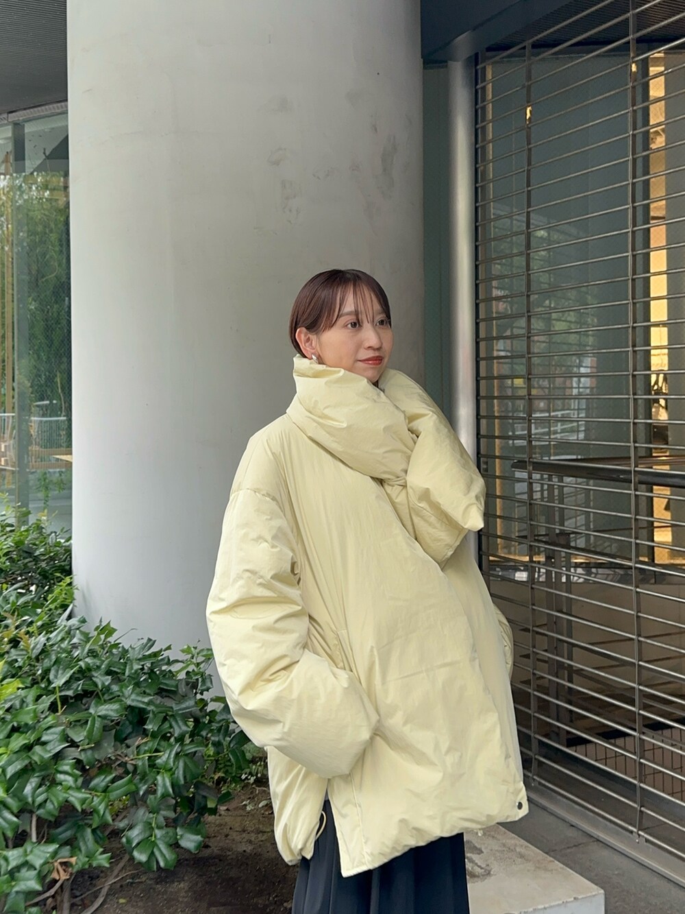 イエロー系のダウンジャケット/コート、グレー系のワンピース、ブラック系のブーツを着用したレディースの夏コーディネートの3枚目の写真