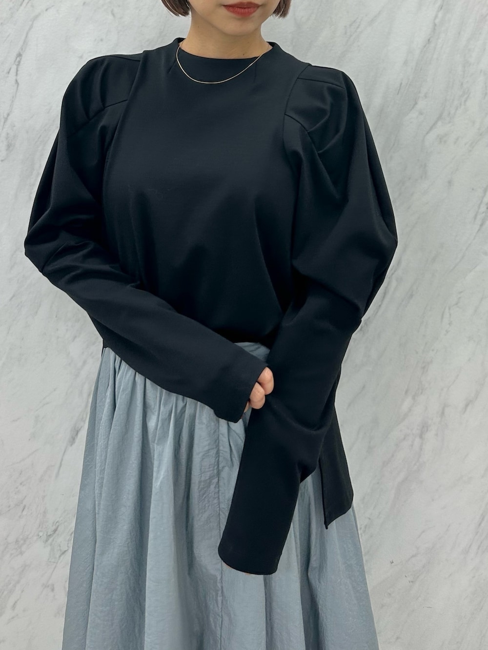 ブルー系のスカート、ブラック系のTシャツ/カットソー、ブラック系のブーツを着用したレディースの秋コーディネートの6枚目の写真