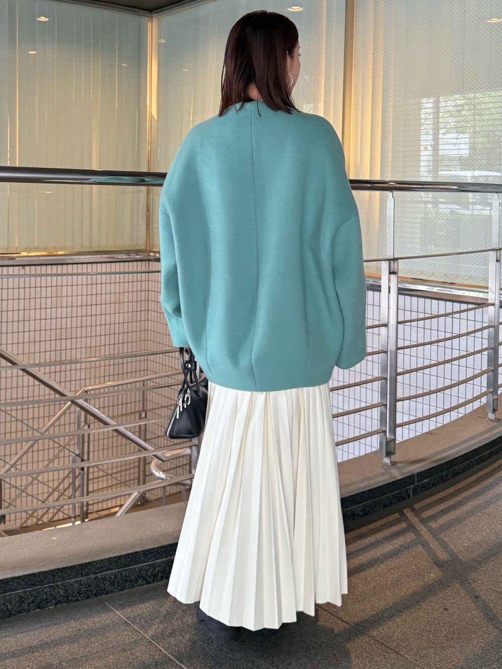 ホワイト系のニット/セーター、ホワイト系のスカート、グリーン系のノーカラージャケットを着用したレディースの秋コーディネートの4枚目の写真