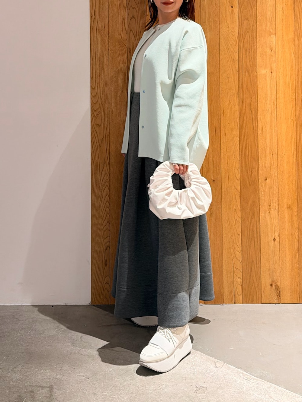 グレー系のスカート、ホワイト系のスニーカー、ホワイト系のハンドバッグを着用したレディースの冬コーディネートの3枚目の写真