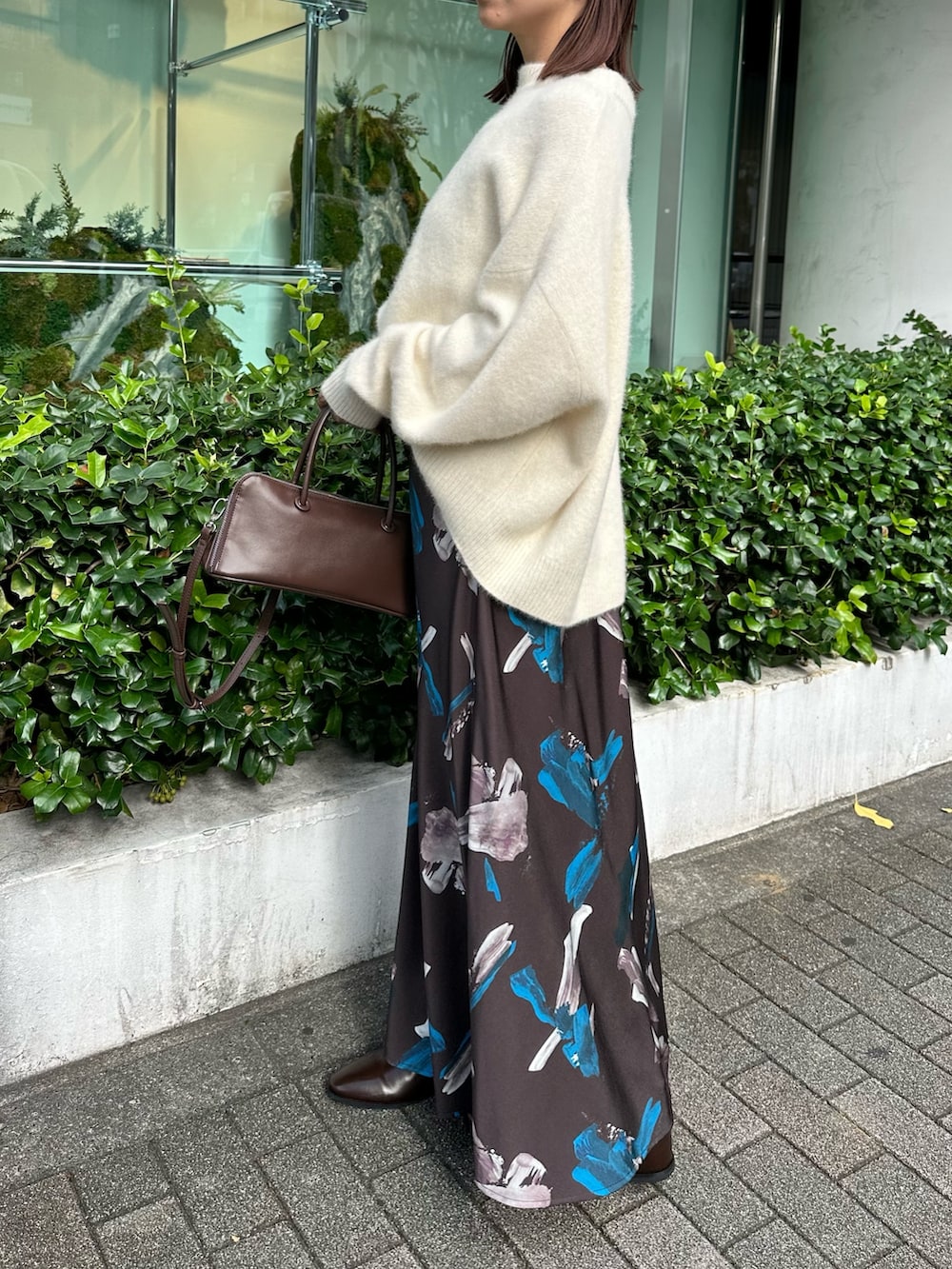 ホワイト系のニット/セーター、ブラウン系のスカート、ブラウン系のボストンバッグを着用したレディースの秋コーディネートの2枚目の写真