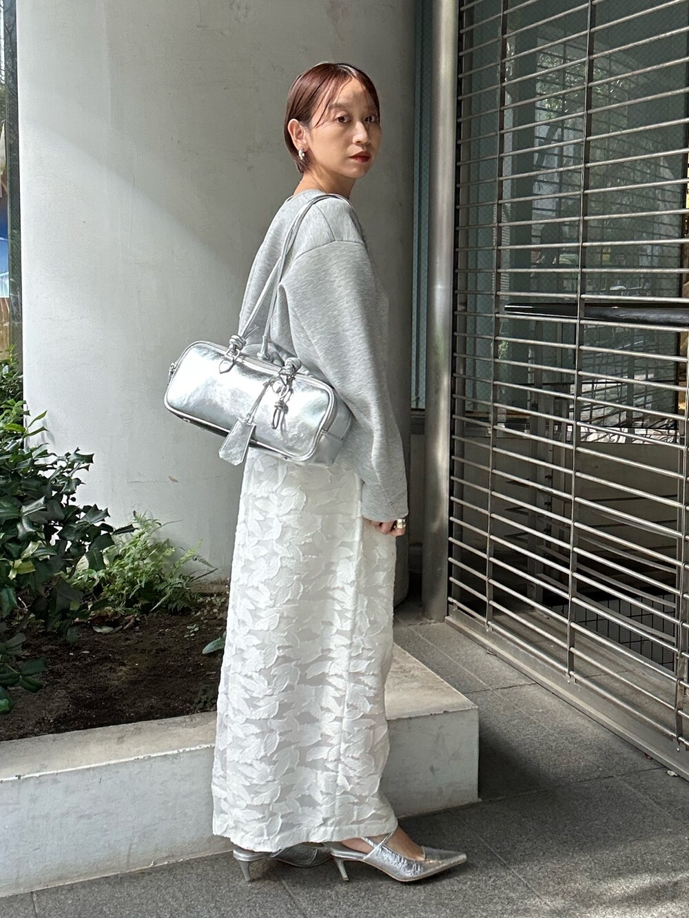 グレー系のスウェット、ホワイト系のスカート、シルバー系のボストンバッグを着用したレディースの冬コーディネートの5枚目の写真