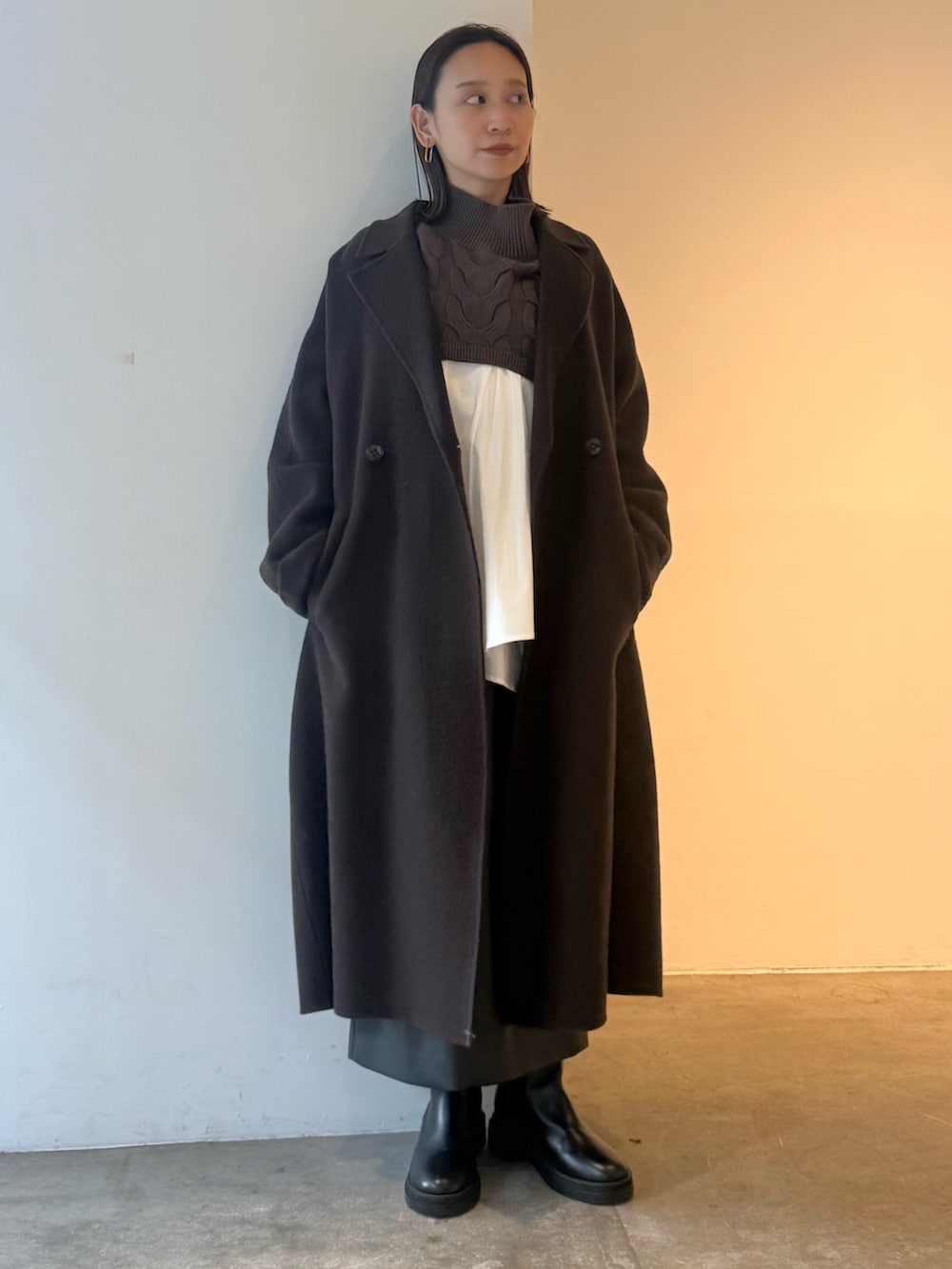 ブラウン系のチェスターコート、ブラック系のスカート、ブラウン系のニット/セーターを着用したレディースの秋コーディネートの2枚目の写真