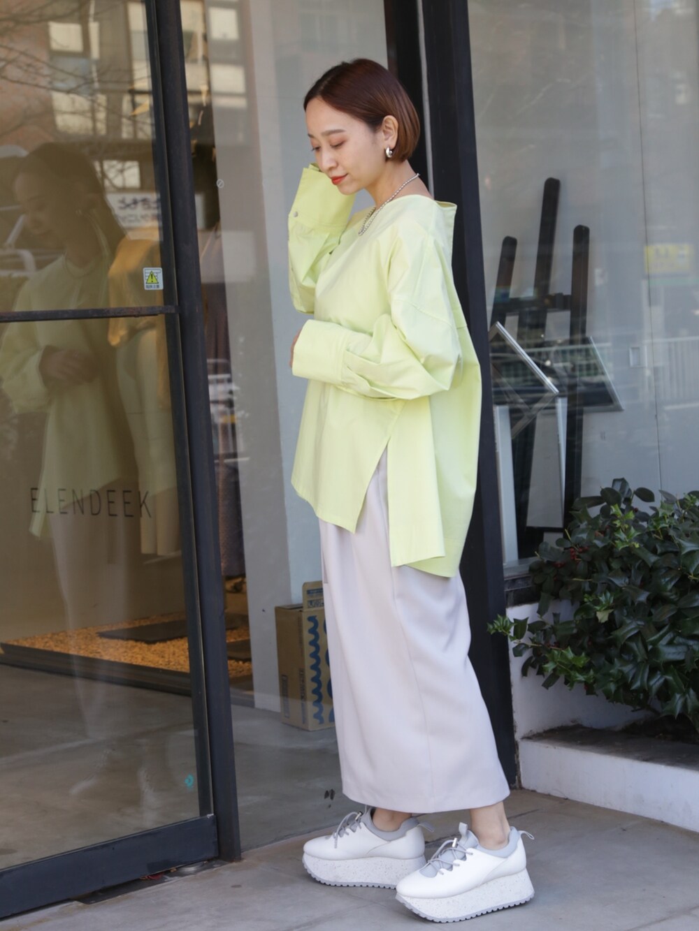 ベージュ系のスカート、ホワイト系のスニーカー、イエロー系のシャツ/ブラウスを着用したレディースの冬コーディネートの4枚目の写真