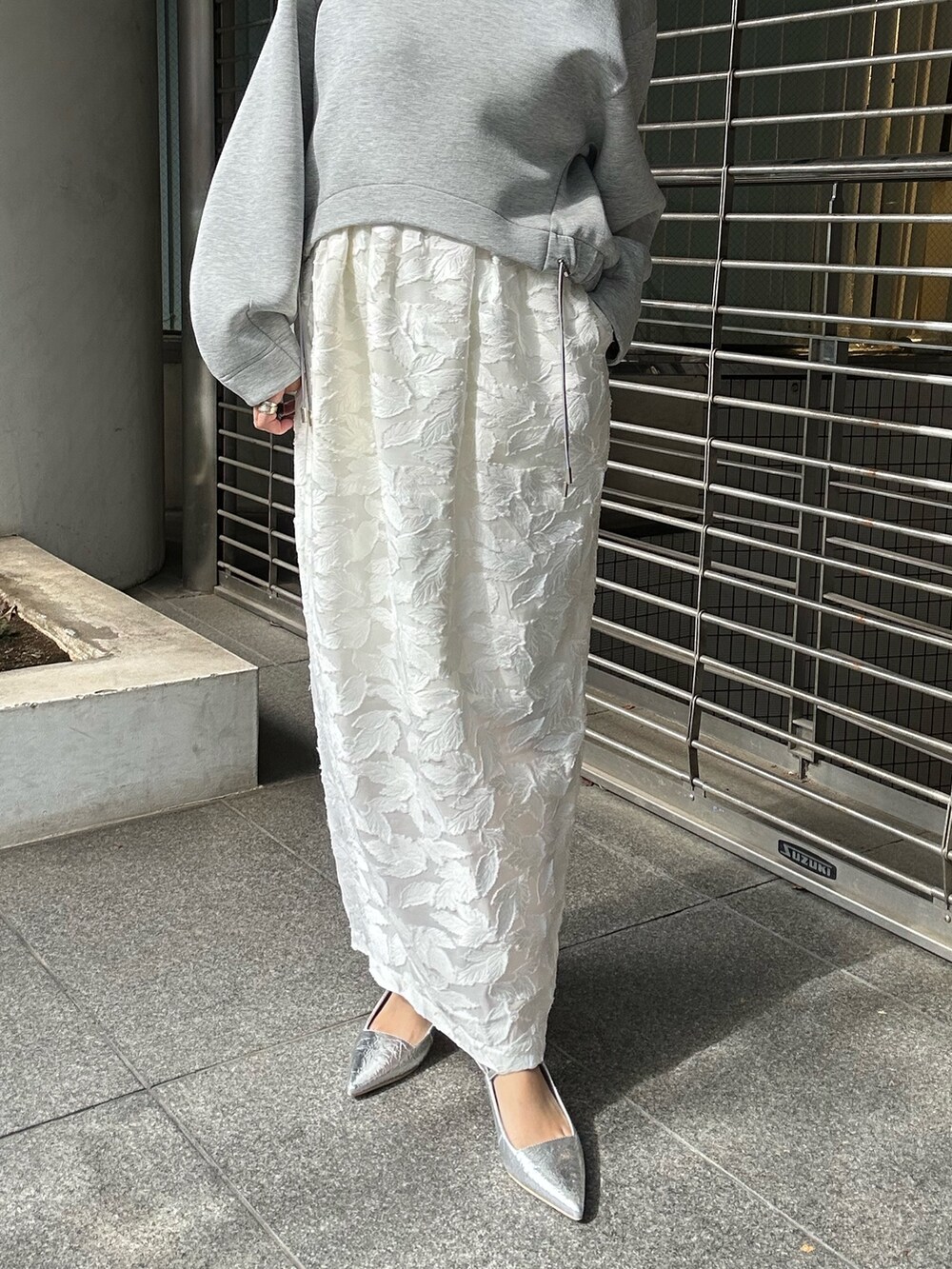 グレー系のスウェット、ホワイト系のスカート、シルバー系のボストンバッグを着用したレディースの冬コーディネートの9枚目の写真