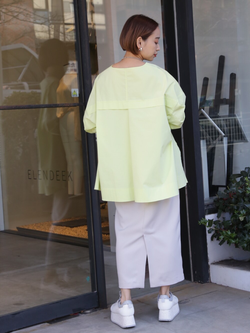 ベージュ系のスカート、ホワイト系のスニーカー、イエロー系のシャツ/ブラウスを着用したレディースの冬コーディネートの5枚目の写真