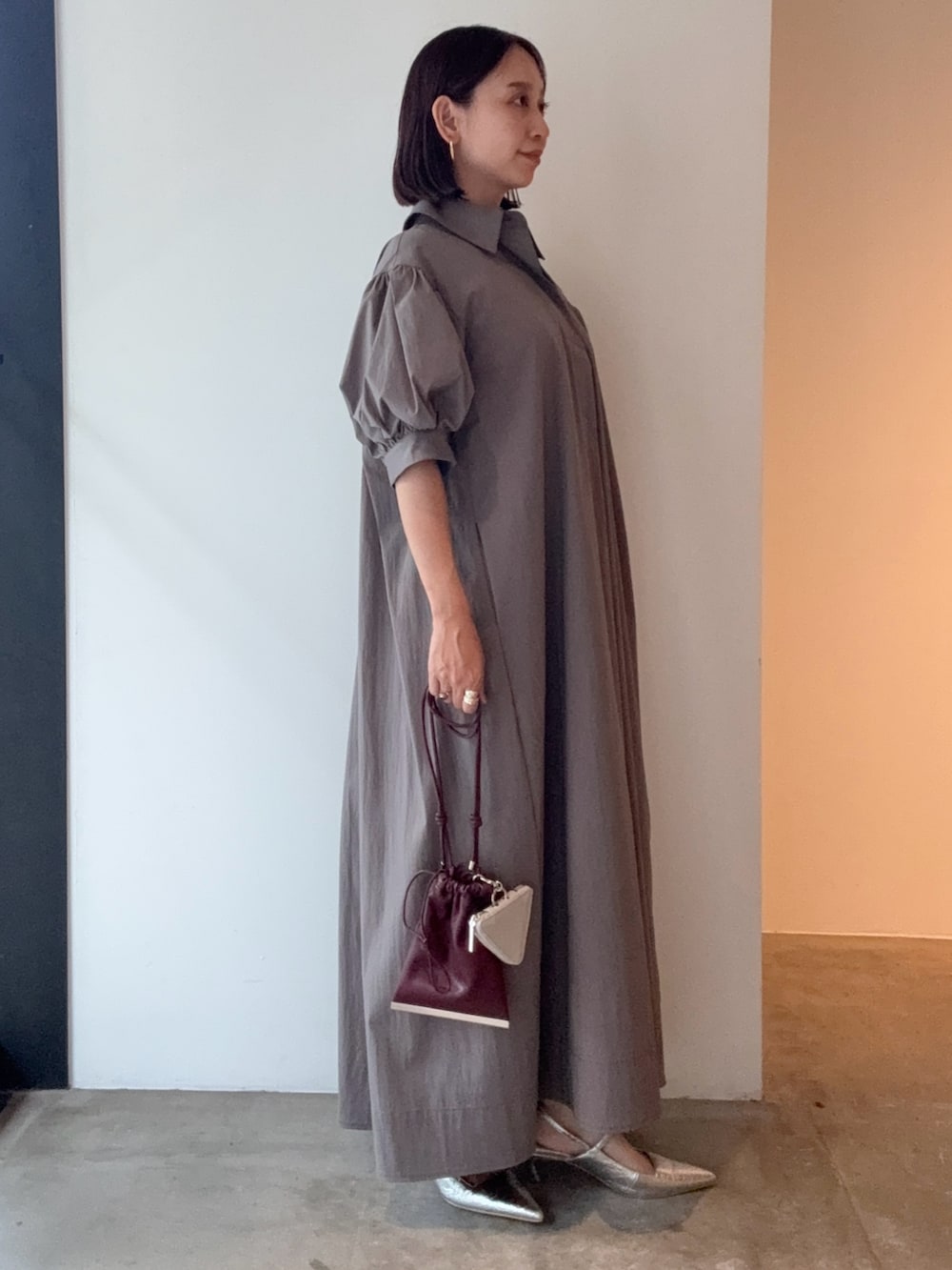 グレー系のワンピース、シルバー系のパンプス、レッド系のショルダーバッグを着用したレディースの夏コーディネートの2枚目の写真