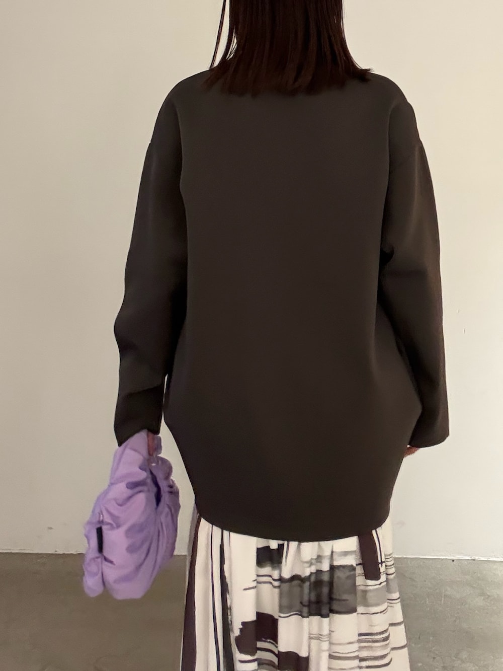 ホワイト系のワンピース、ブラック系のパンプス、パープル系のハンドバッグを着用したレディースの冬コーディネートの6枚目の写真