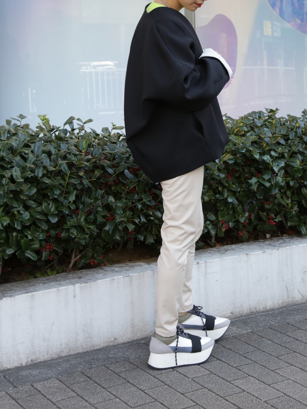 ブラック系のノーカラーコート、ベージュ系のその他パンツ、ブルー系のスニーカーを着用したレディースの冬コーディネートの5枚目の写真