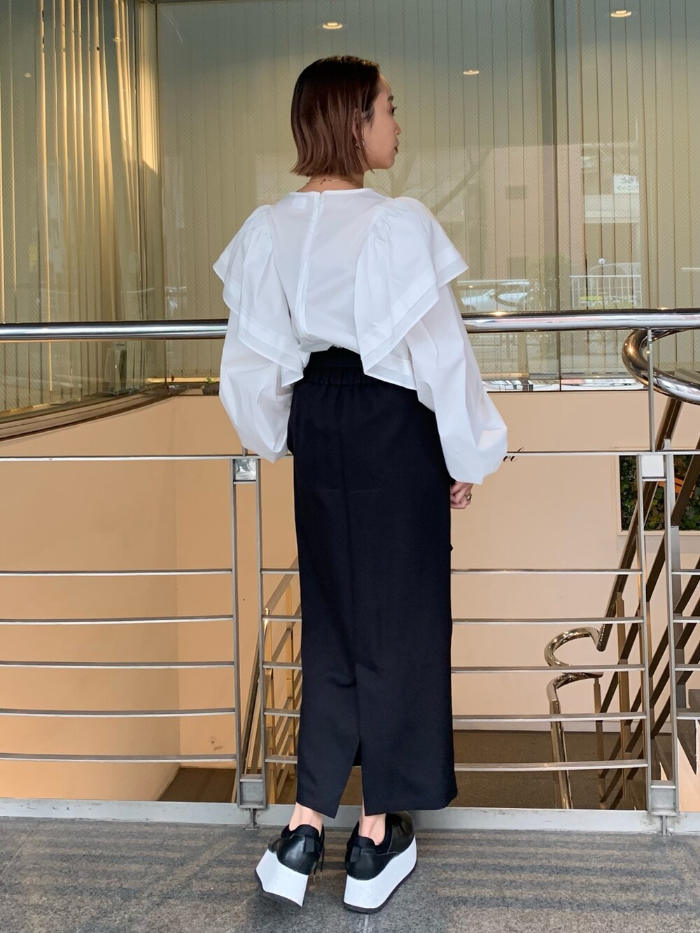 ホワイト系のシャツ/ブラウス、ブラック系のスカート、ブラック系のスニーカーを着用したレディースの春コーディネートの4枚目の写真