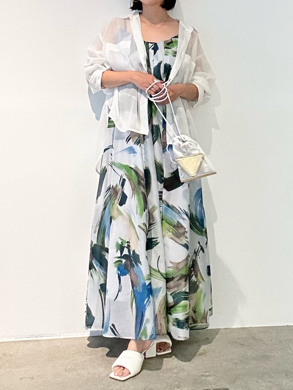 グリーン系のワンピース、ホワイト系のサンダル、ホワイト系のショルダーバッグを着用したレディースの春コーディネートの2枚目の写真