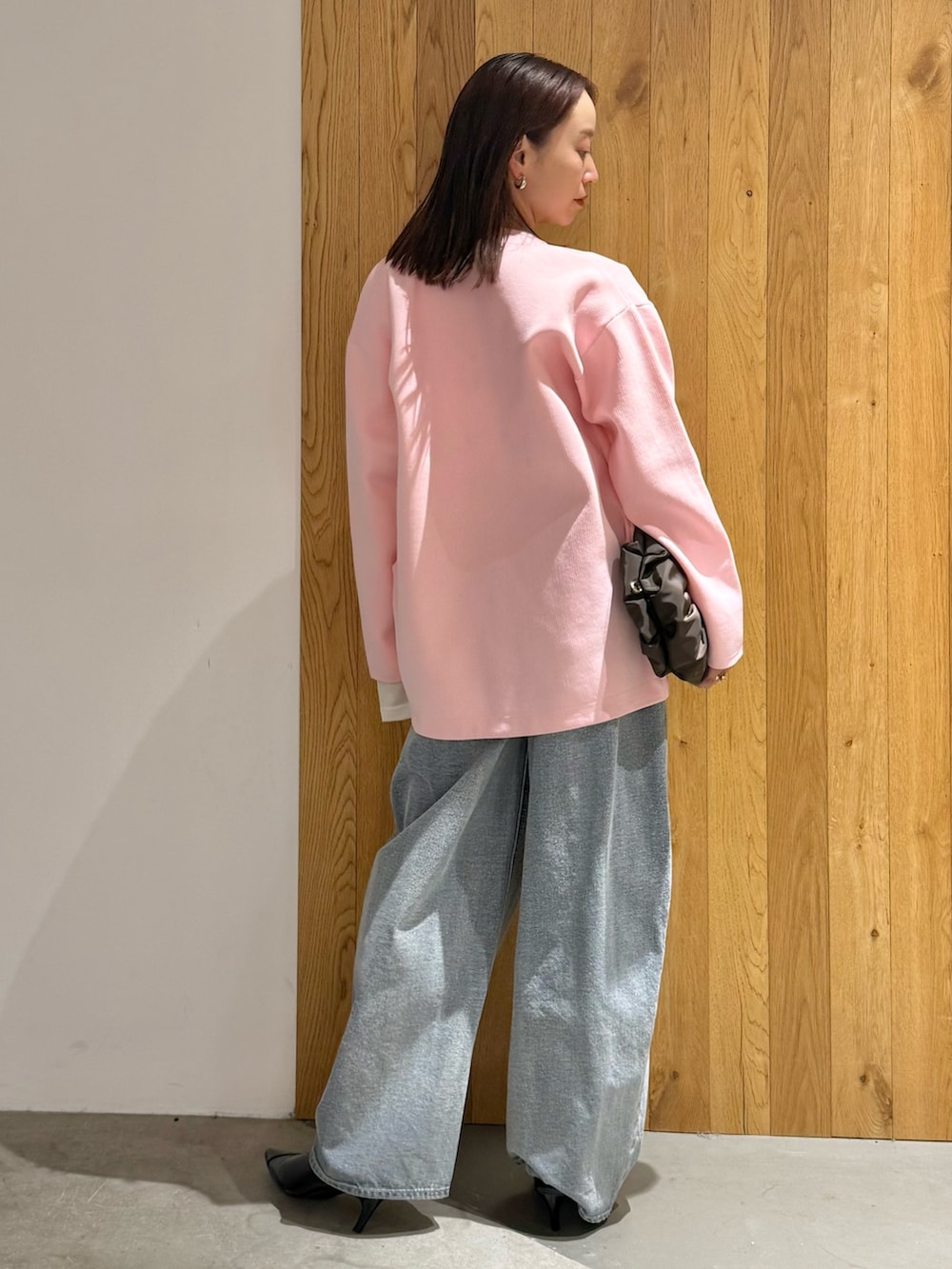 ブルー系のデニムパンツ、ブラック系のパンプス、ピンク系のカーディガン/ボレロを着用したレディースの冬コーディネートの3枚目の写真