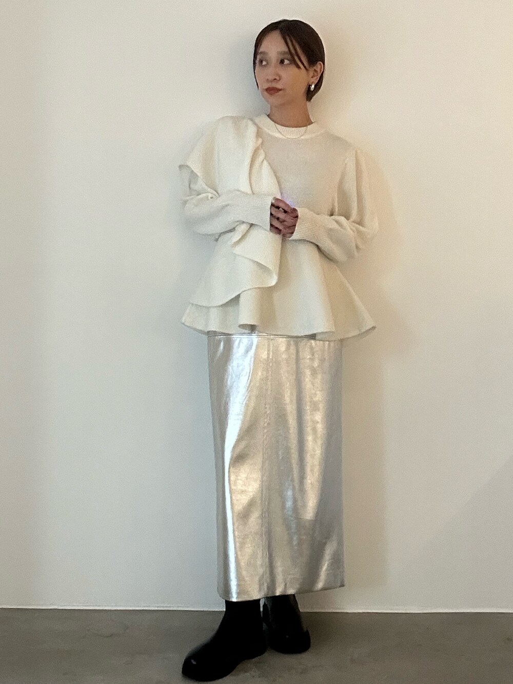 ホワイト系のニット/セーター、ブラック系のブーツ、シルバー系のスカートを着用したレディースの秋コーディネートの6枚目の写真