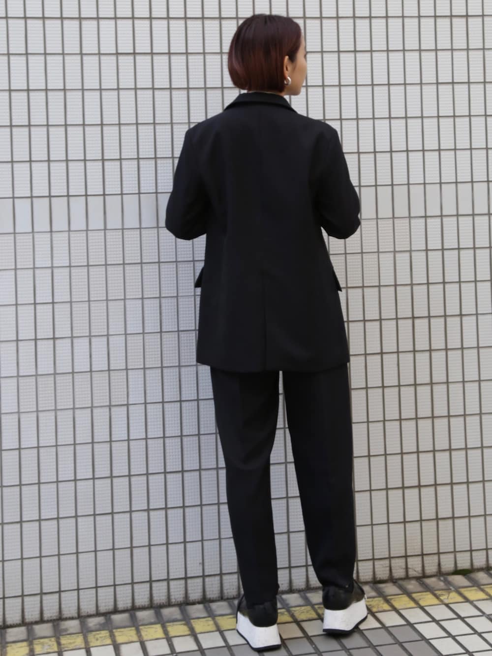 ブラック系のテーラードジャケット、ブラック系のその他パンツ、ホワイト系のスニーカーを着用したレディースの冬コーディネートの3枚目の写真