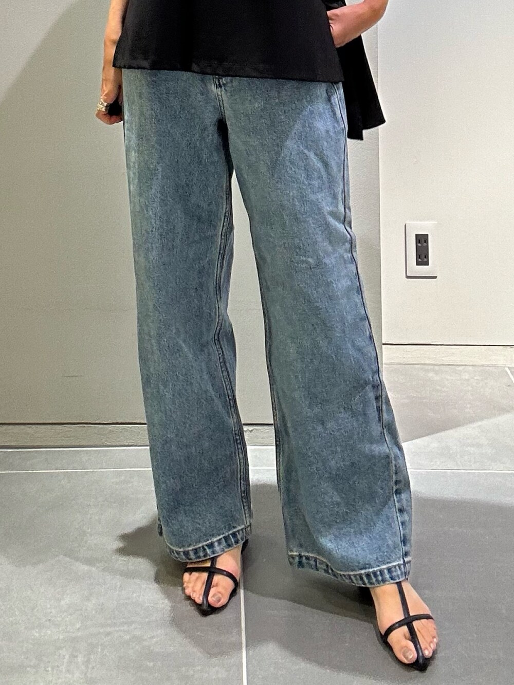 ブルー系のデニムパンツ、シルバー系のハンドバッグ、ブラック系のタンクトップを着用したレディースの夏コーディネートの9枚目の写真
